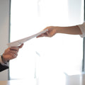 Colleagues transferring printed documents hand to hand