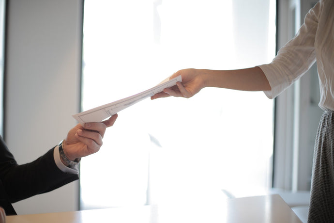 Colleagues transferring printed documents hand to hand